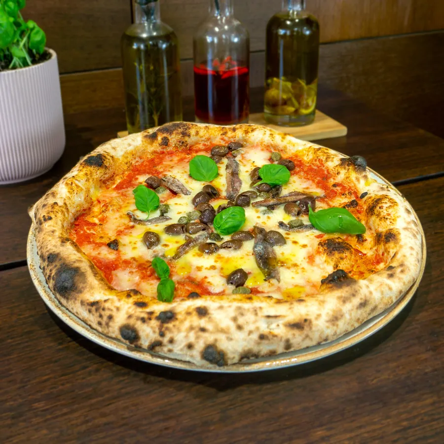Pizza Napoli mit Sardellen, Kapern und Oliven.